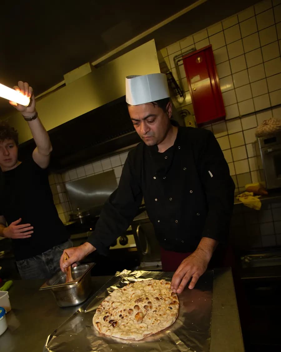De chef van Nepal Delight bakt naanbrood in de keuken
